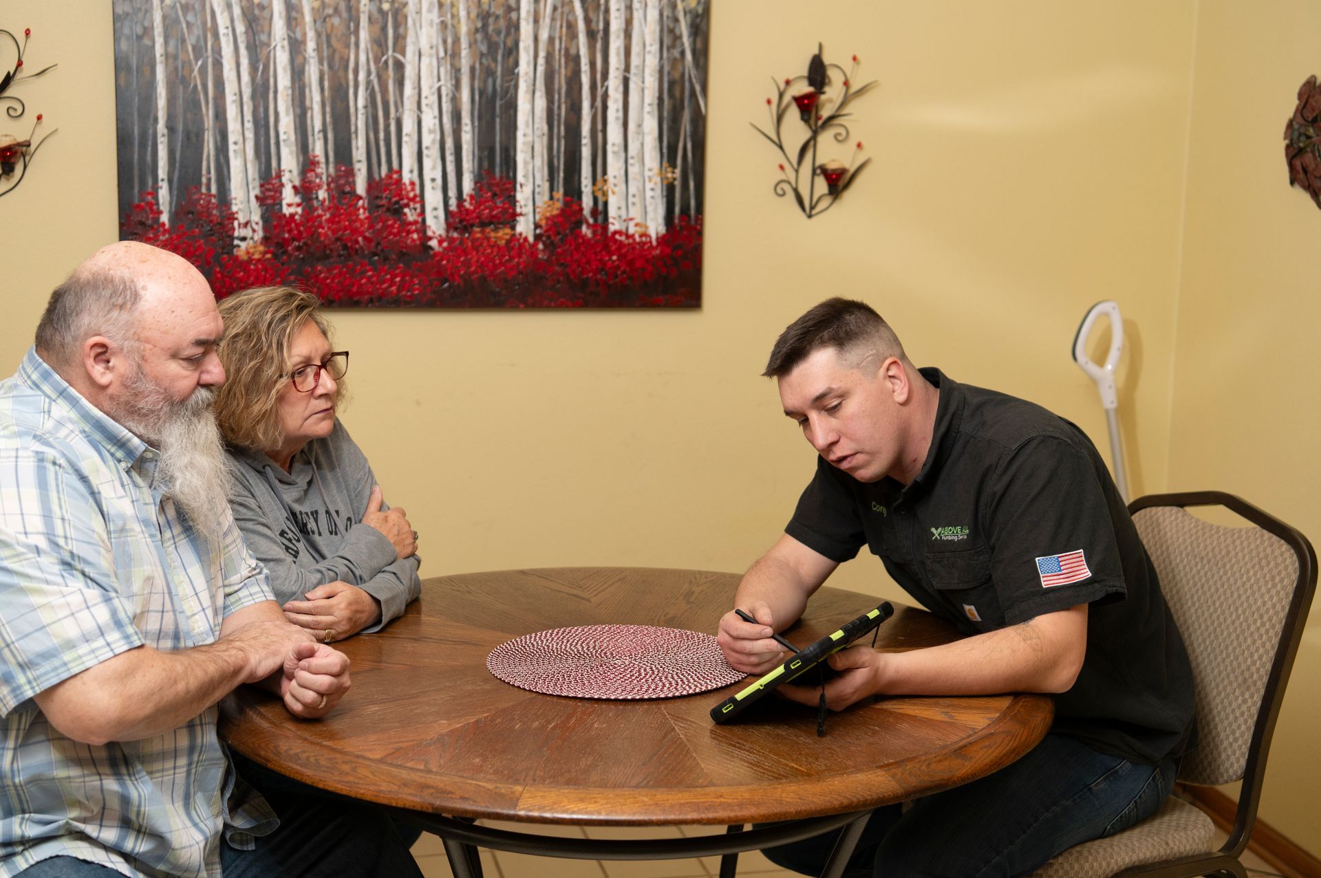 A man is sitting at a table talking to two people.