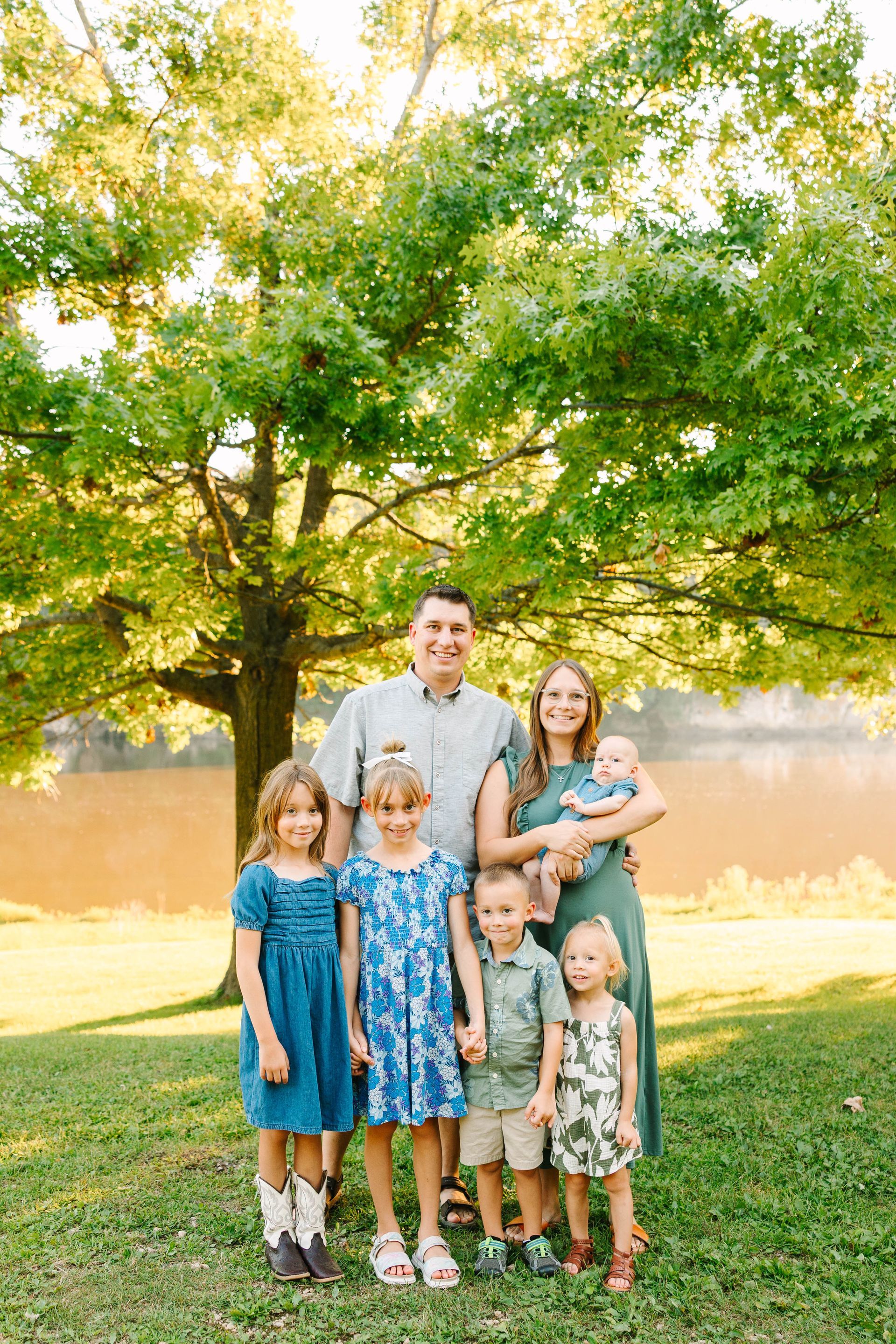 A family is posing for a picture together on a dirt road.