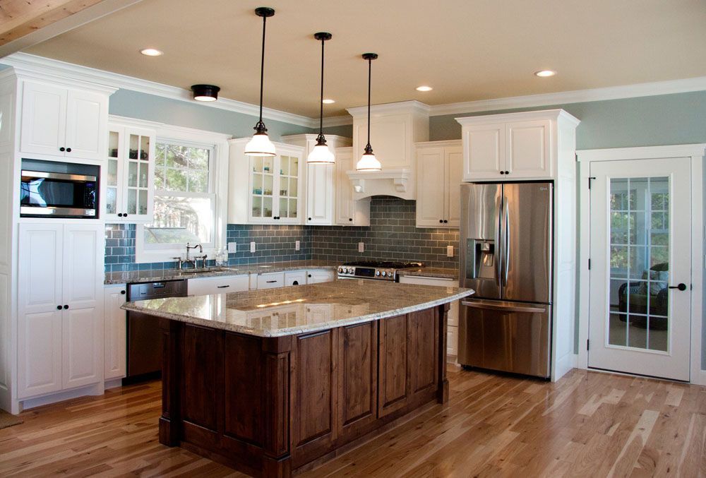 Kitchen with white cabinets, wood island, and stainless steel appliances. Blue backsplash and light wood floors.