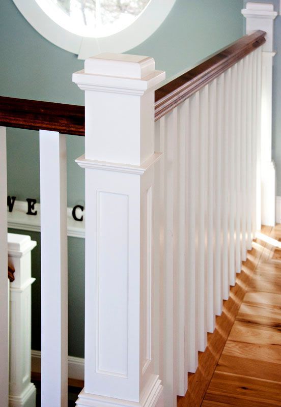 White staircase with wood handrail, leading up.  Wood flooring.  Bright sunlight.