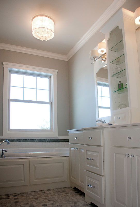 Bathroom with white cabinets, light fixtures, and a window.
