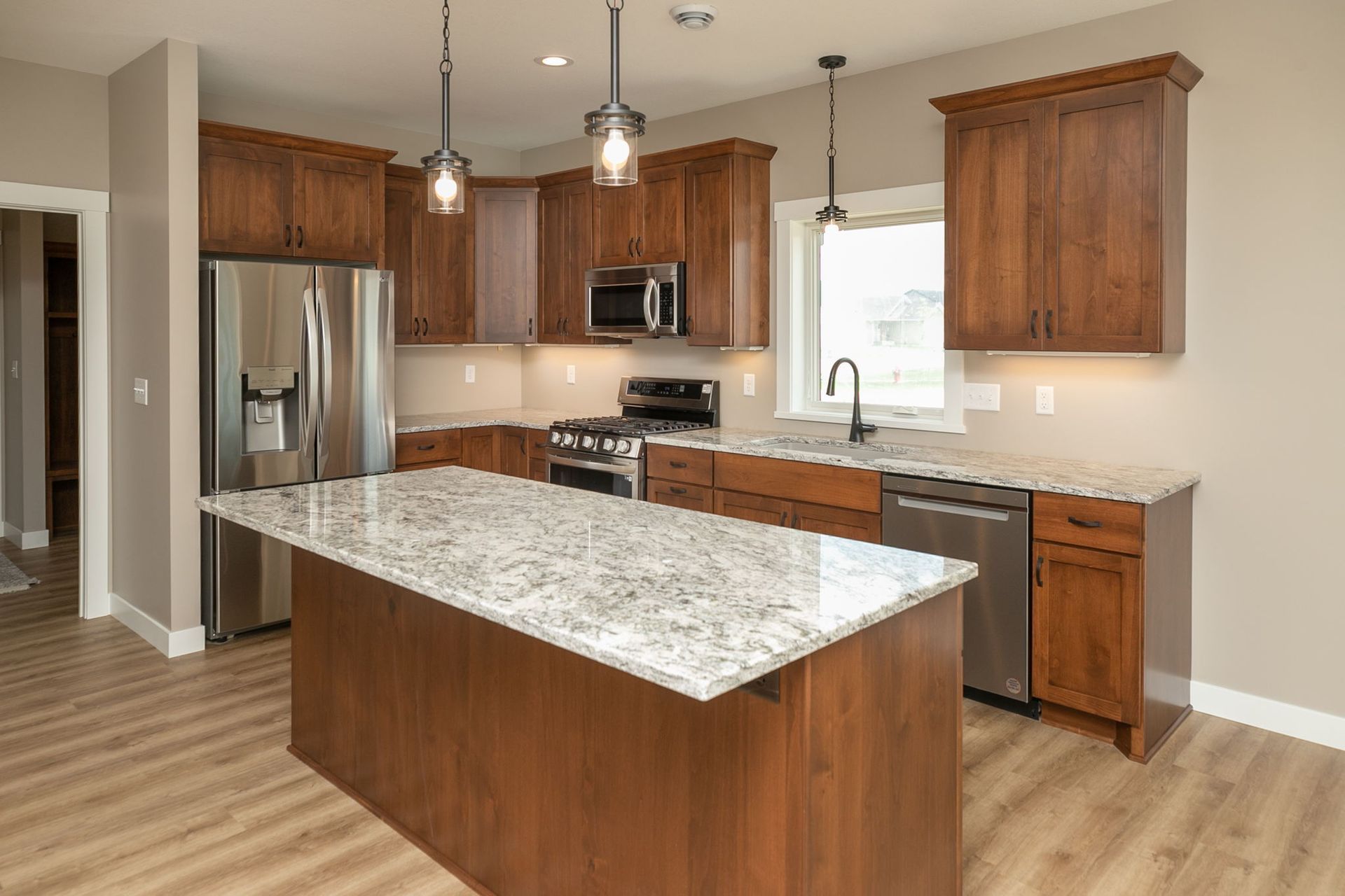 Kitchen with brown cabinets, stainless steel appliances, granite countertops, and an island.