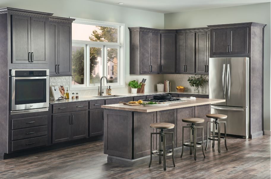Gray kitchen with dark cabinets, stainless steel appliances, and island with stools.