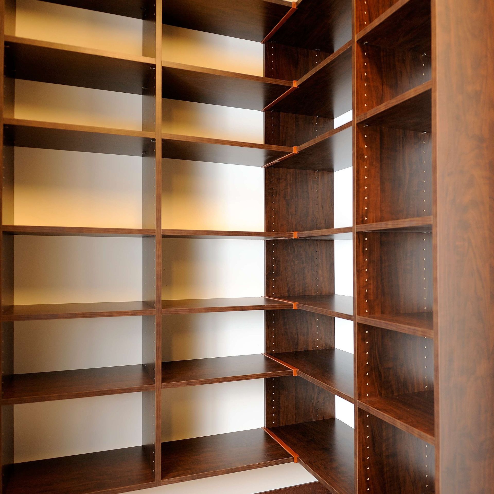 Wooden built-in shelving unit, corner design, with several shelves and vertical supports.