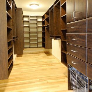 Walk-in closet with dark wood shelving, drawers, and light wood flooring.