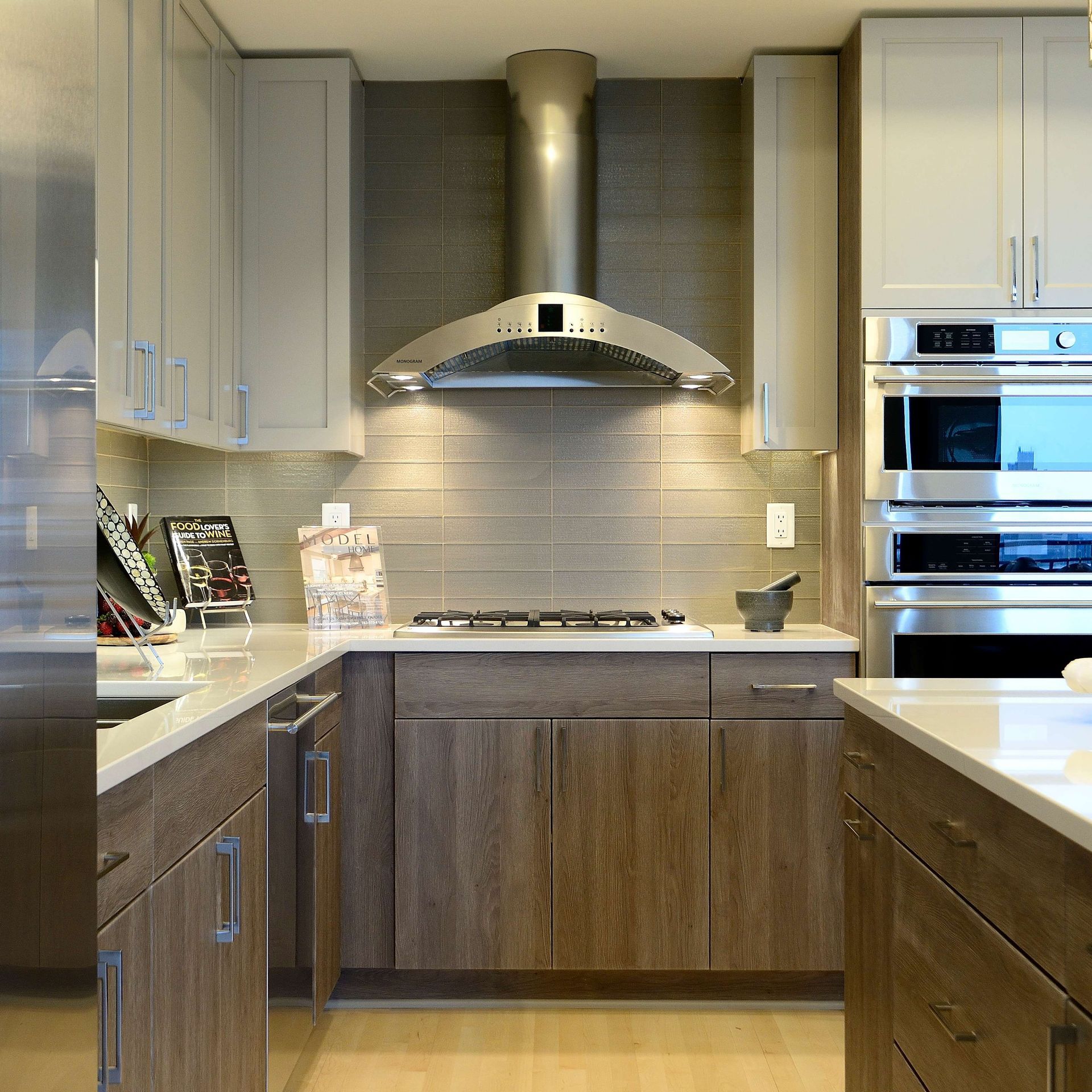 Modern kitchen with wood and light gray cabinets, stainless steel appliances, and backsplash.