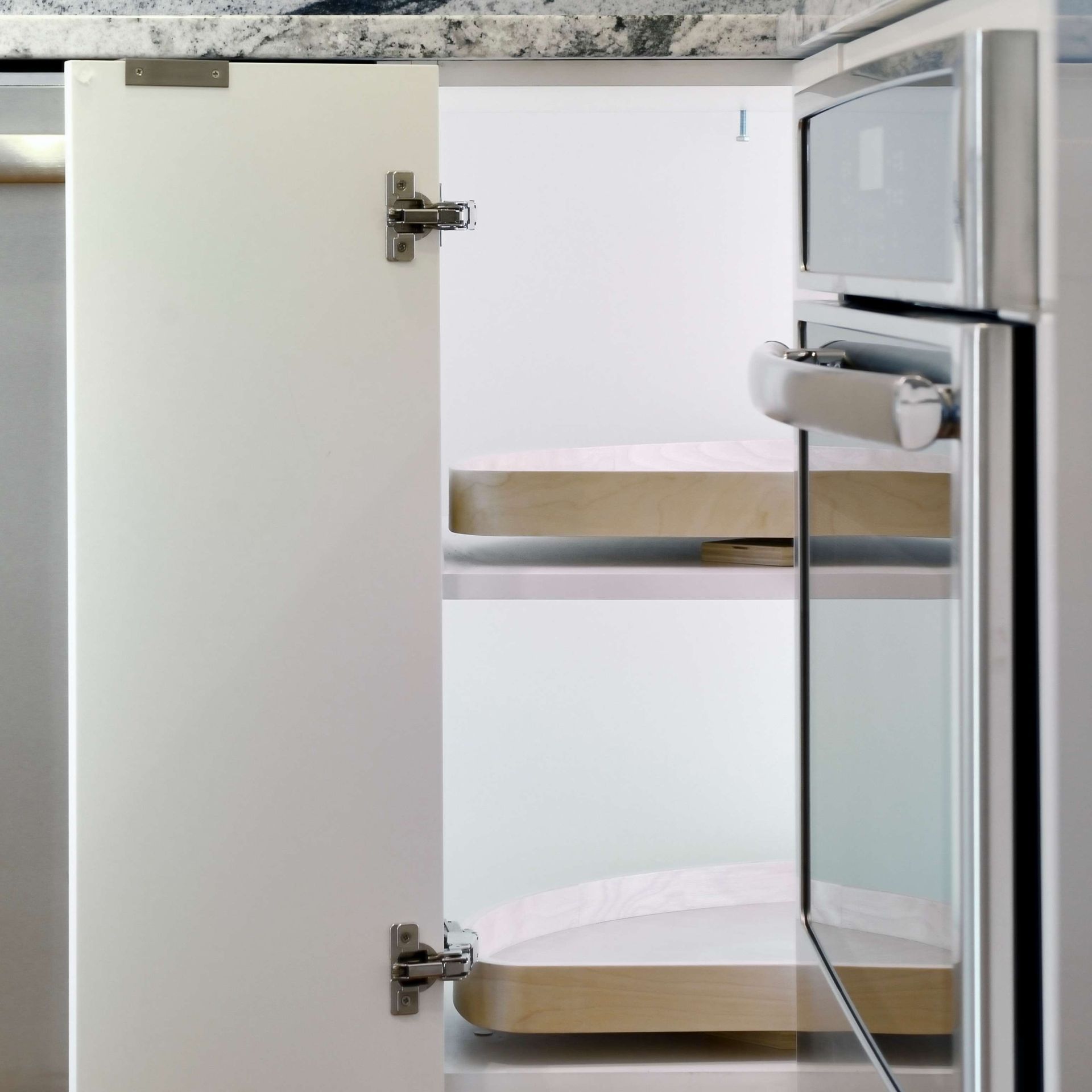 White cabinet door open, revealing two wooden shelves inside. A built-in oven is visible to the right.