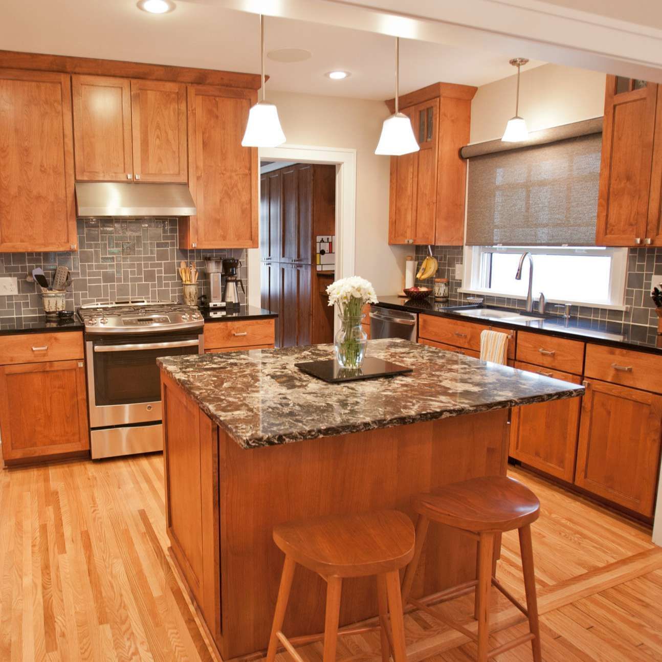 Kitchen with wooden cabinets, island with countertop, stainless steel appliances, and two stools.