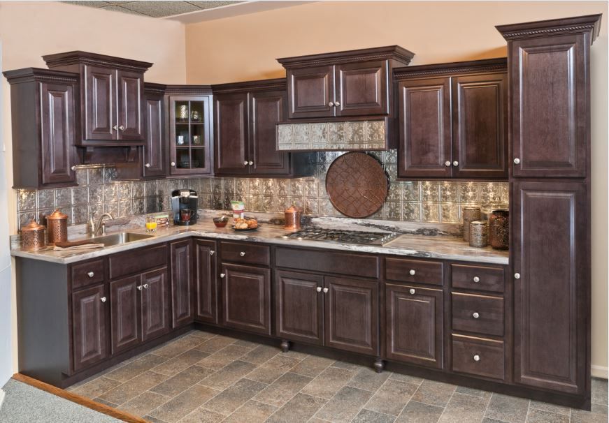 Dark wood kitchen cabinets with a decorative backsplash and stone-look flooring.