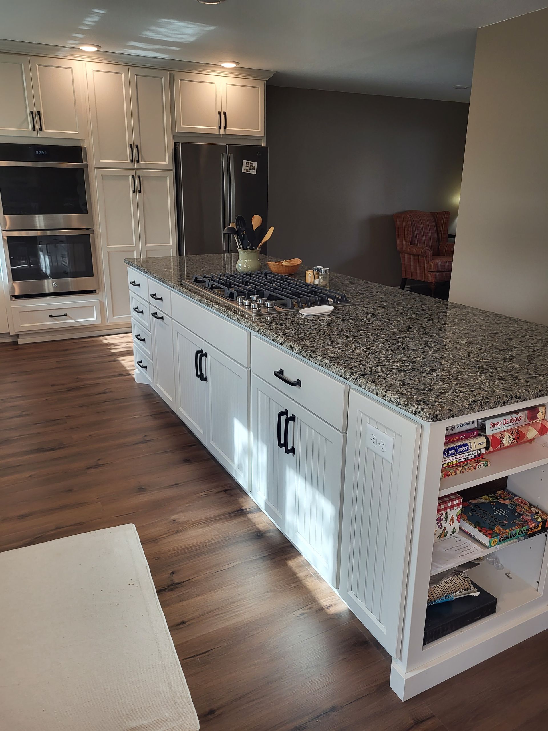 Kitchen with white cabinets, dark granite countertop island, and stainless steel appliances.