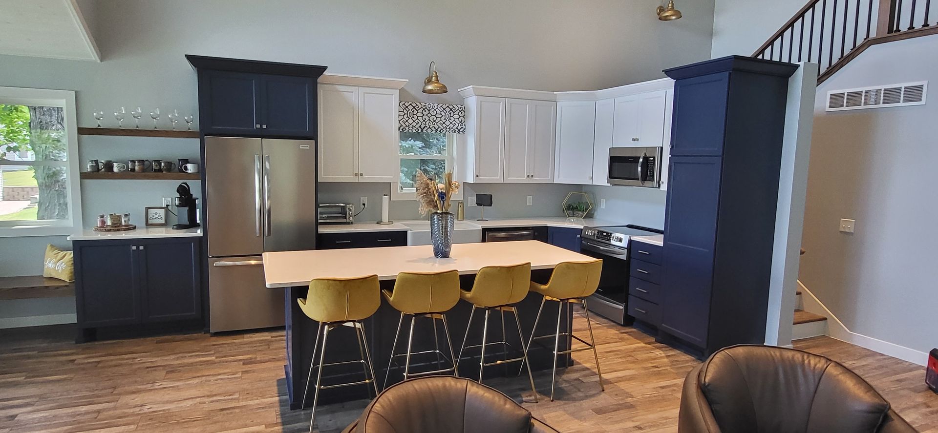 Kitchen with navy and white cabinets, stainless steel appliances, and yellow barstools around the island.