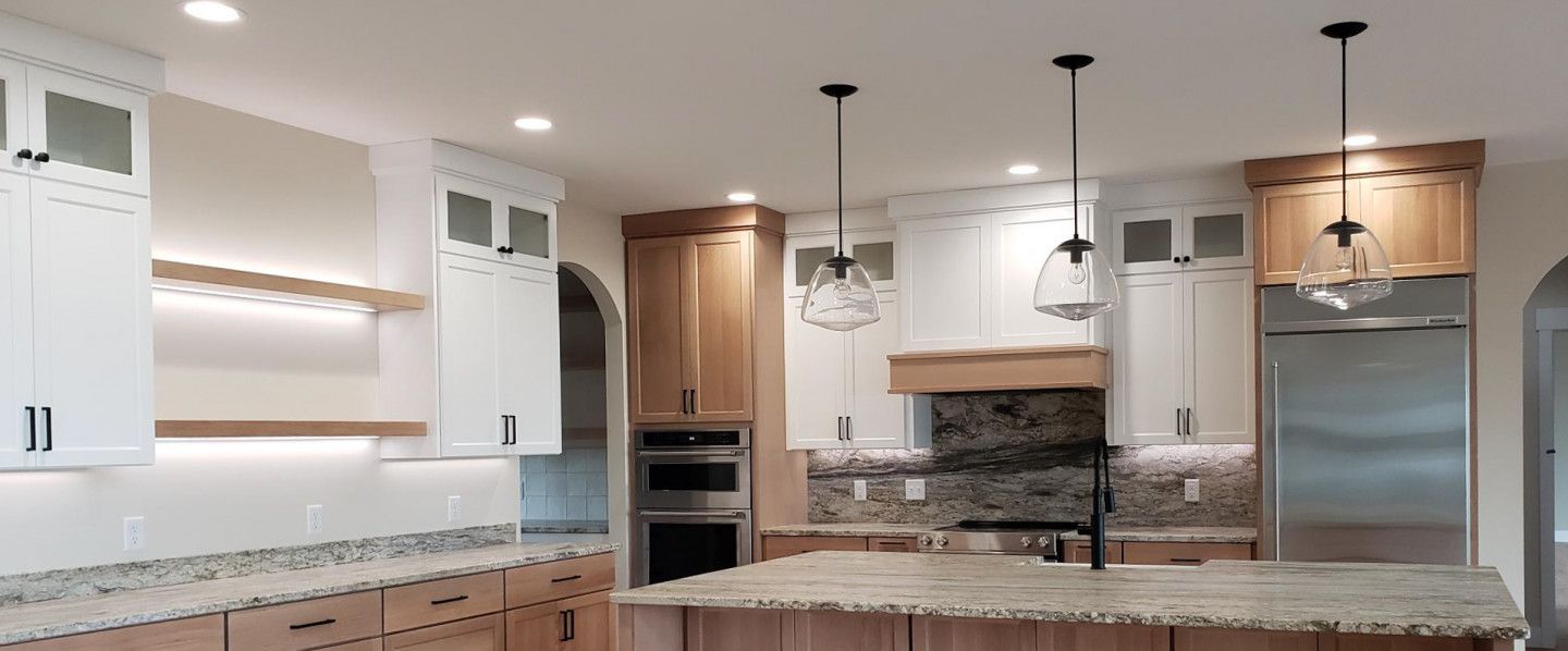 Kitchen with light-colored cabinets, granite countertops, and pendant lights over an island.