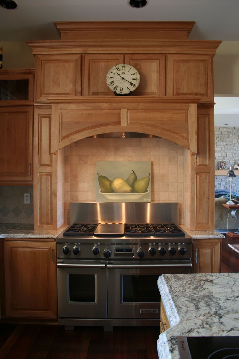 Kitchen with stainless steel stove, wooden cabinets, and a painting of pears.