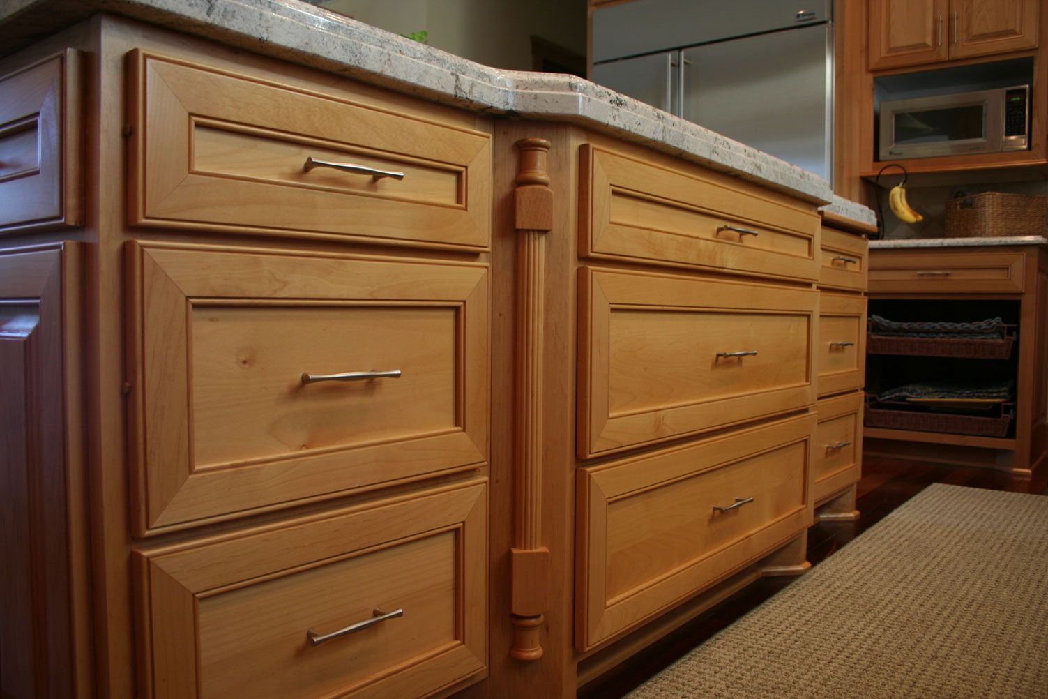 Wooden kitchen cabinets with granite countertop and stainless steel handles.