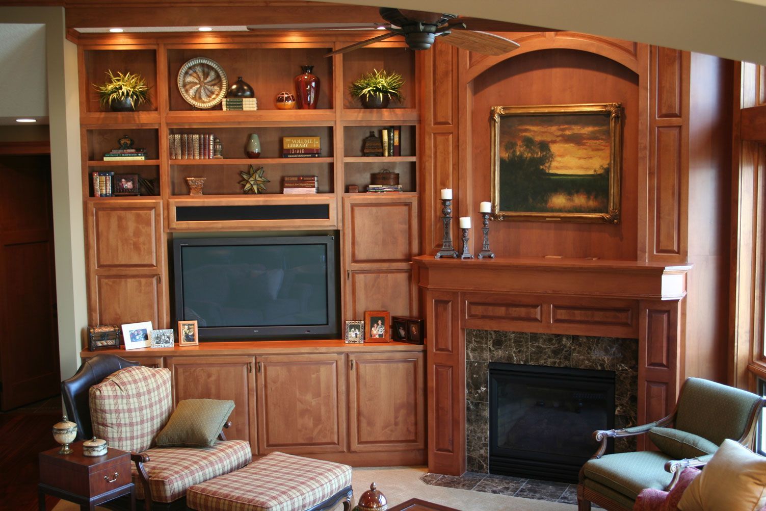 Built-in wooden entertainment center with fireplace, TV, and display shelves in a living room.
