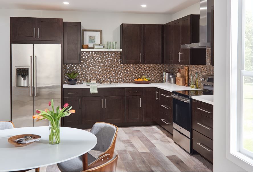 Dark brown kitchen with stainless steel appliances, white countertops, and wood floors.