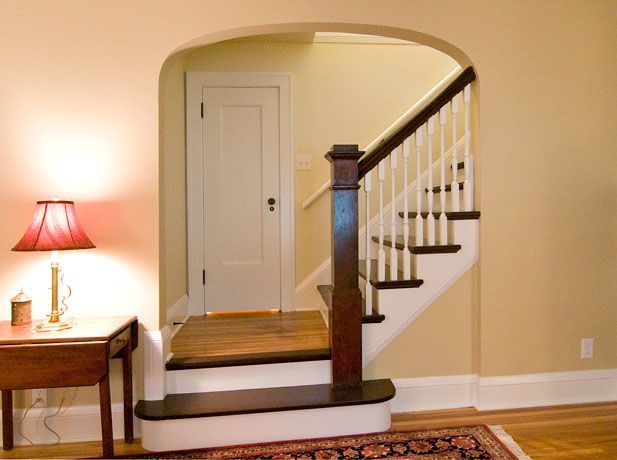 Entryway with stairs leading up, a door, and a table with a lamp.