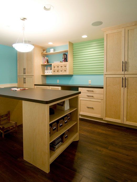 Craft room with a large island, cabinets, and a blue and green wall.