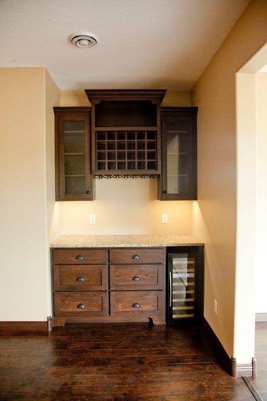 Built-in wine bar with wooden cabinets, a wine rack, and a small wine fridge.
