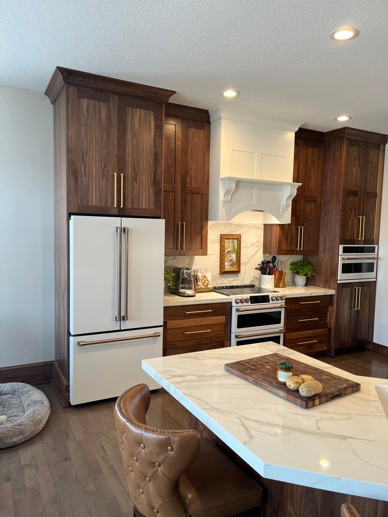 Modern kitchen with dark wood cabinets, white refrigerator, and marble island.