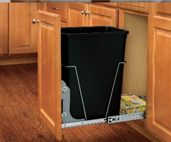 Trash can on a pull-out track inside a kitchen cabinet, with the cabinet door open.