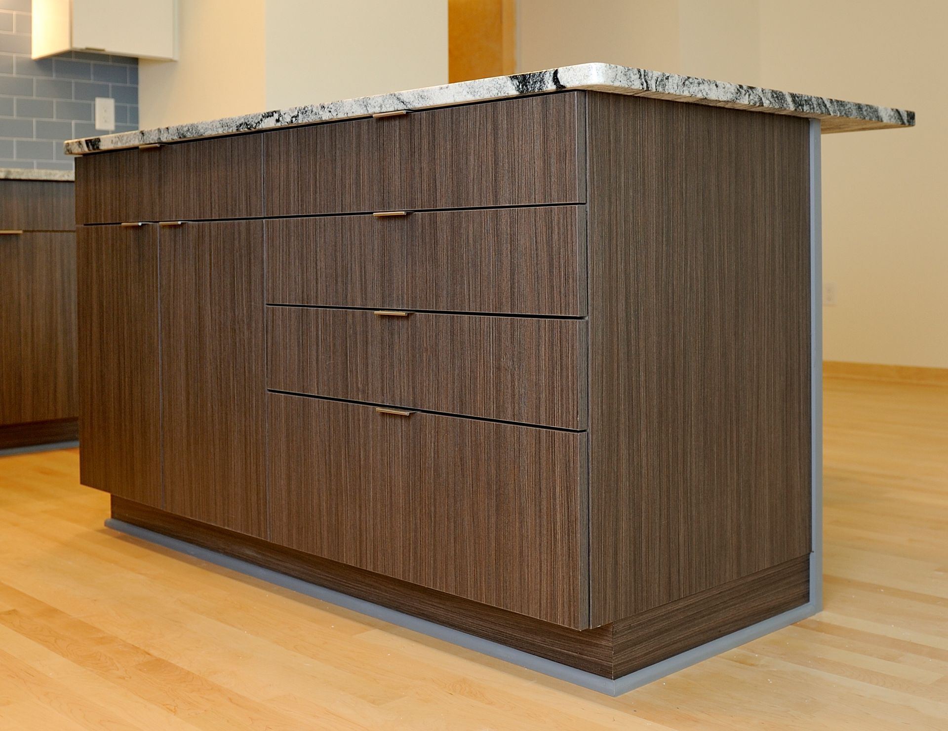 Kitchen island with dark wood grain cabinets, granite countertop, and horizontal drawer pulls.