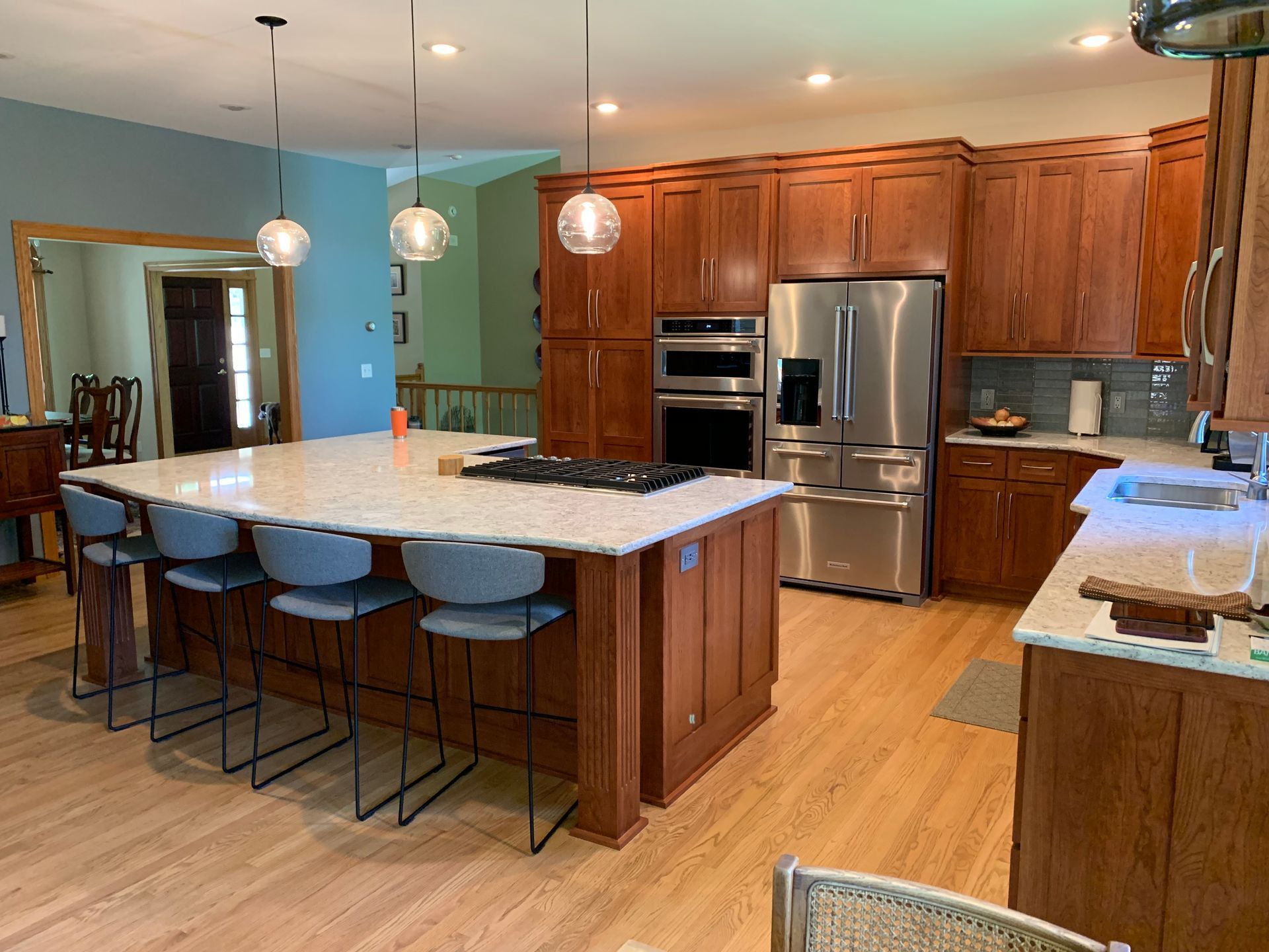 Kitchen with wood cabinets, stainless steel appliances, large island with seating, and pendant lights.