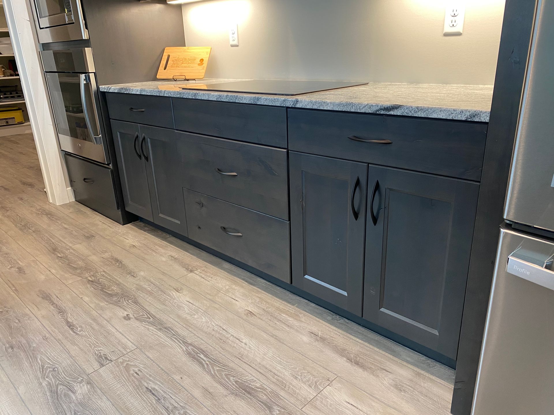 Gray kitchen cabinets with a granite countertop and cooktop.