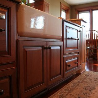 Kitchen cabinetry with a farmhouse sink and ornate wooden doors and drawers.