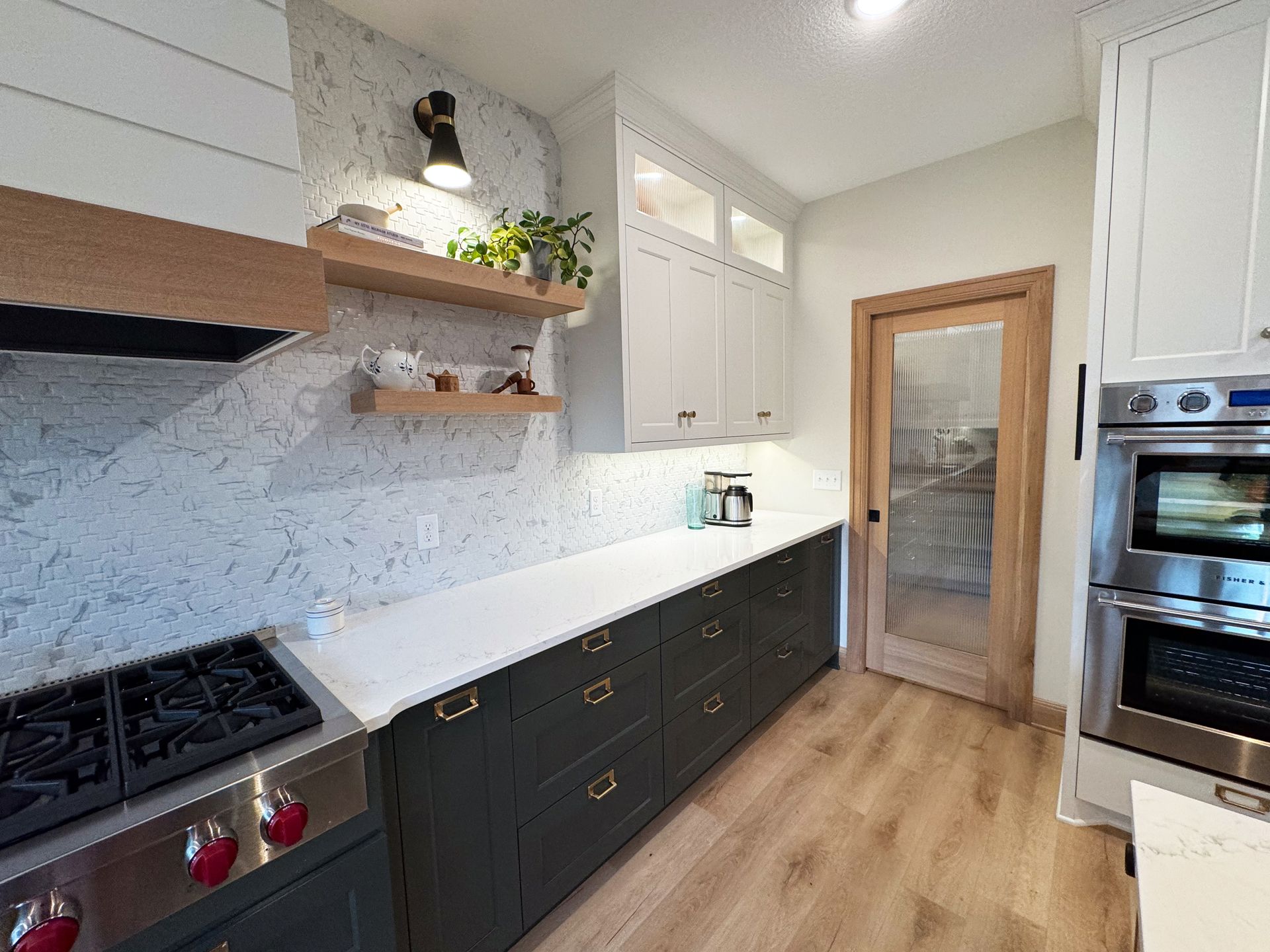 Modern kitchen with dark green cabinets, white countertops, and wood accents.