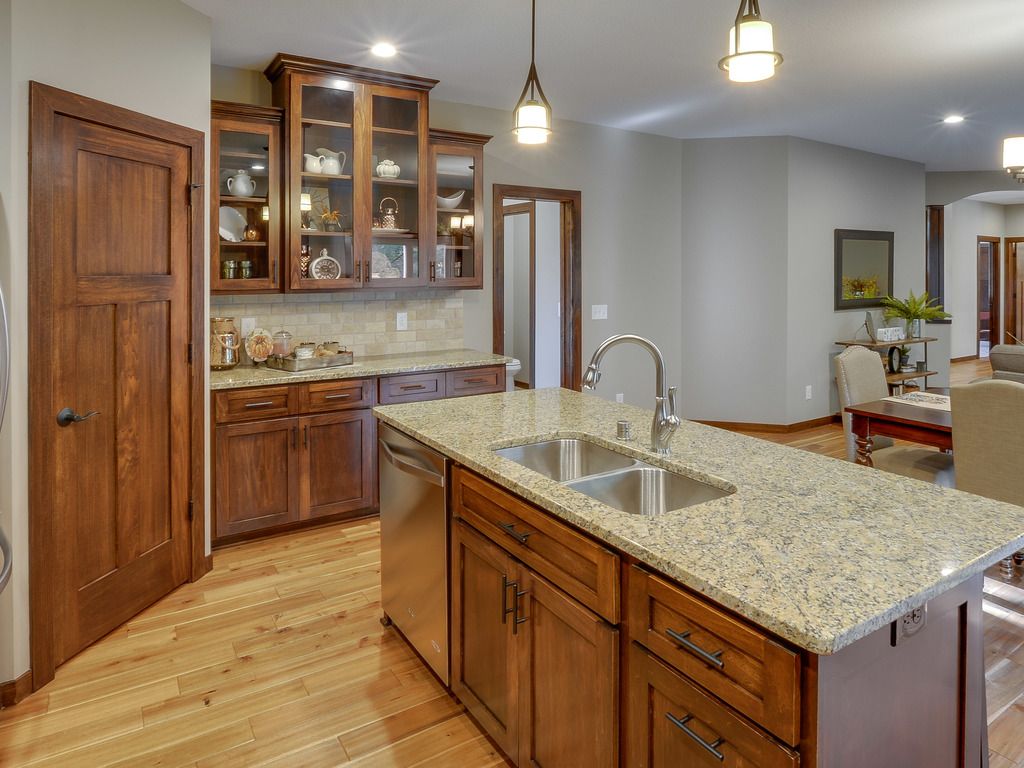 Kitchen with wooden cabinets, granite countertops, and island with stainless steel sink.