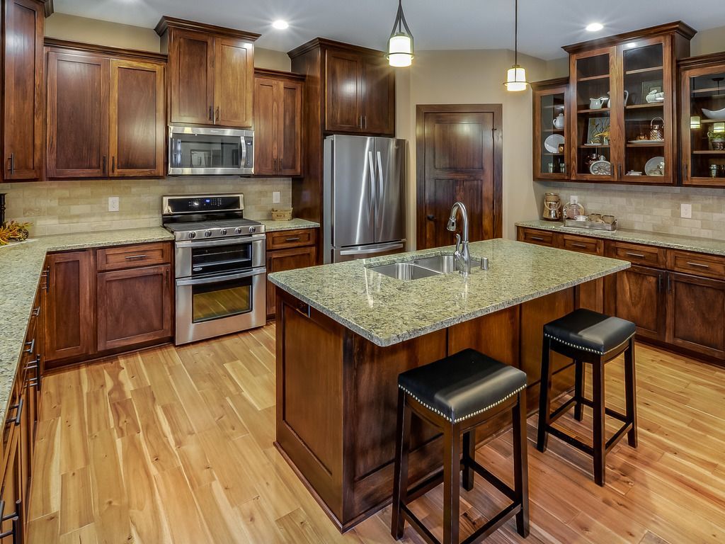 Kitchen with dark wood cabinets, stainless steel appliances, granite countertops, and hardwood floors.