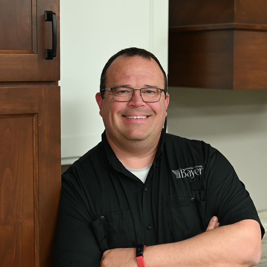 Man wearing glasses smiles outdoors with green background.