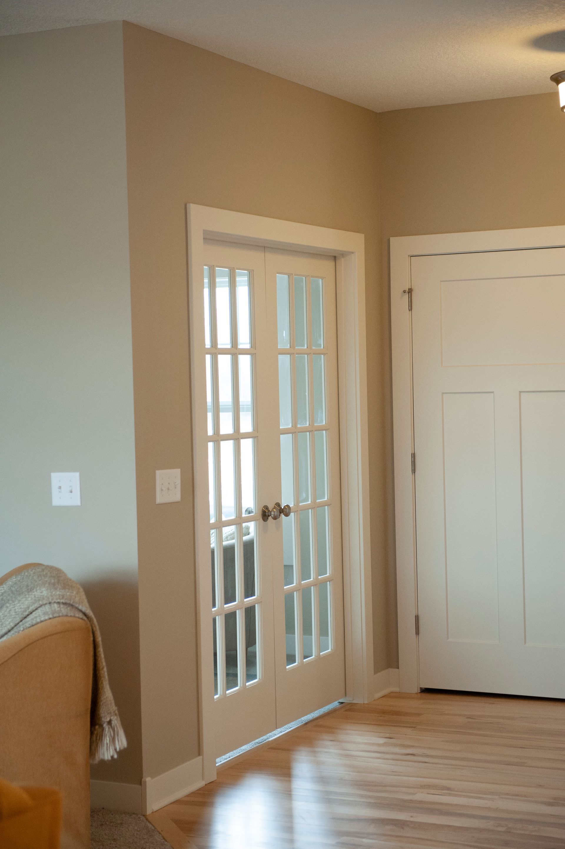 Interior view: French doors, white trim, beige walls, hardwood floors.
