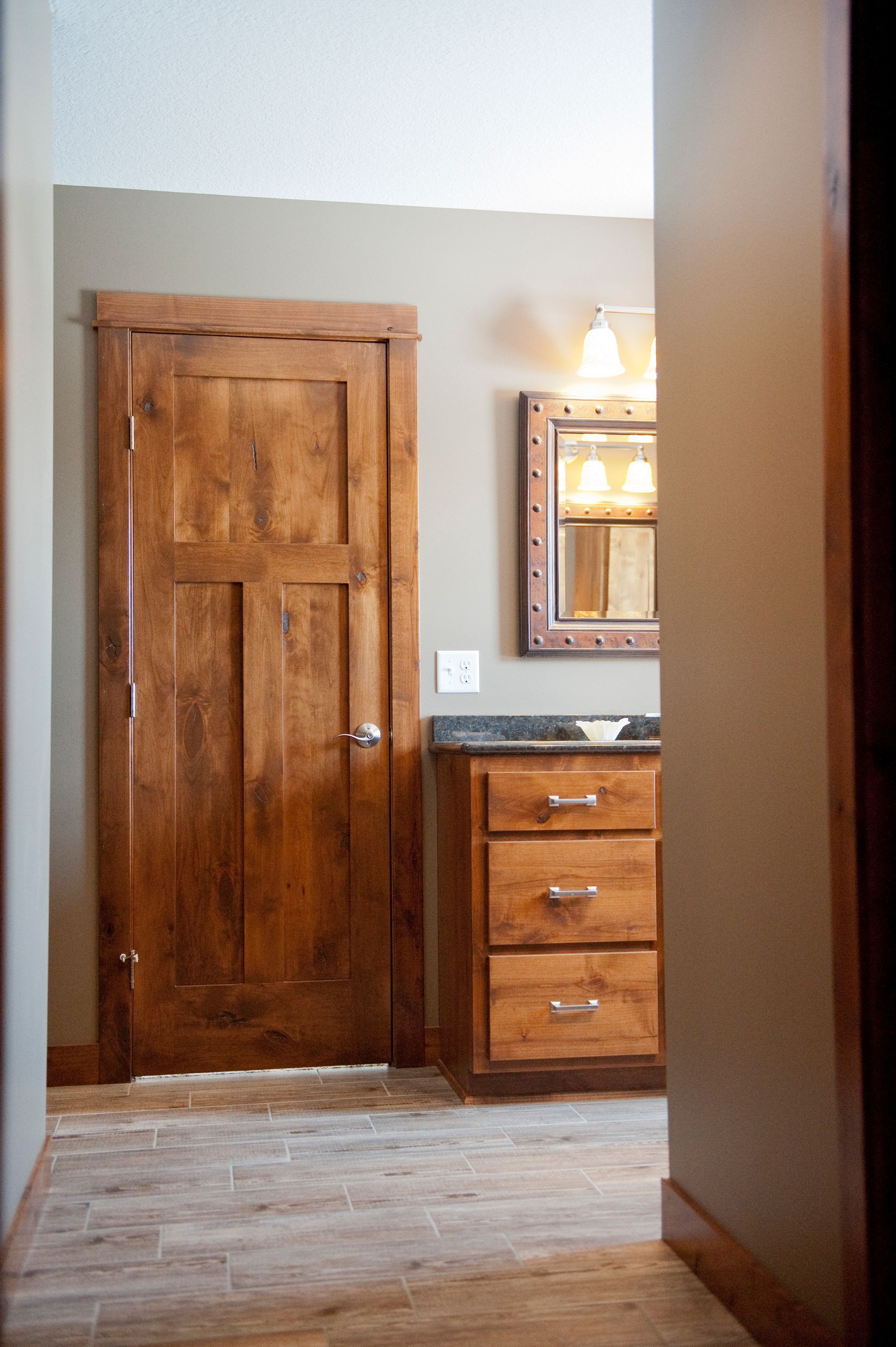 Wooden door and vanity in a bathroom, neutral colors, wood trim and flooring.