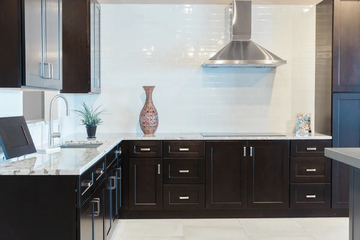 Dark brown kitchen cabinets with white countertops and a stainless steel range hood.