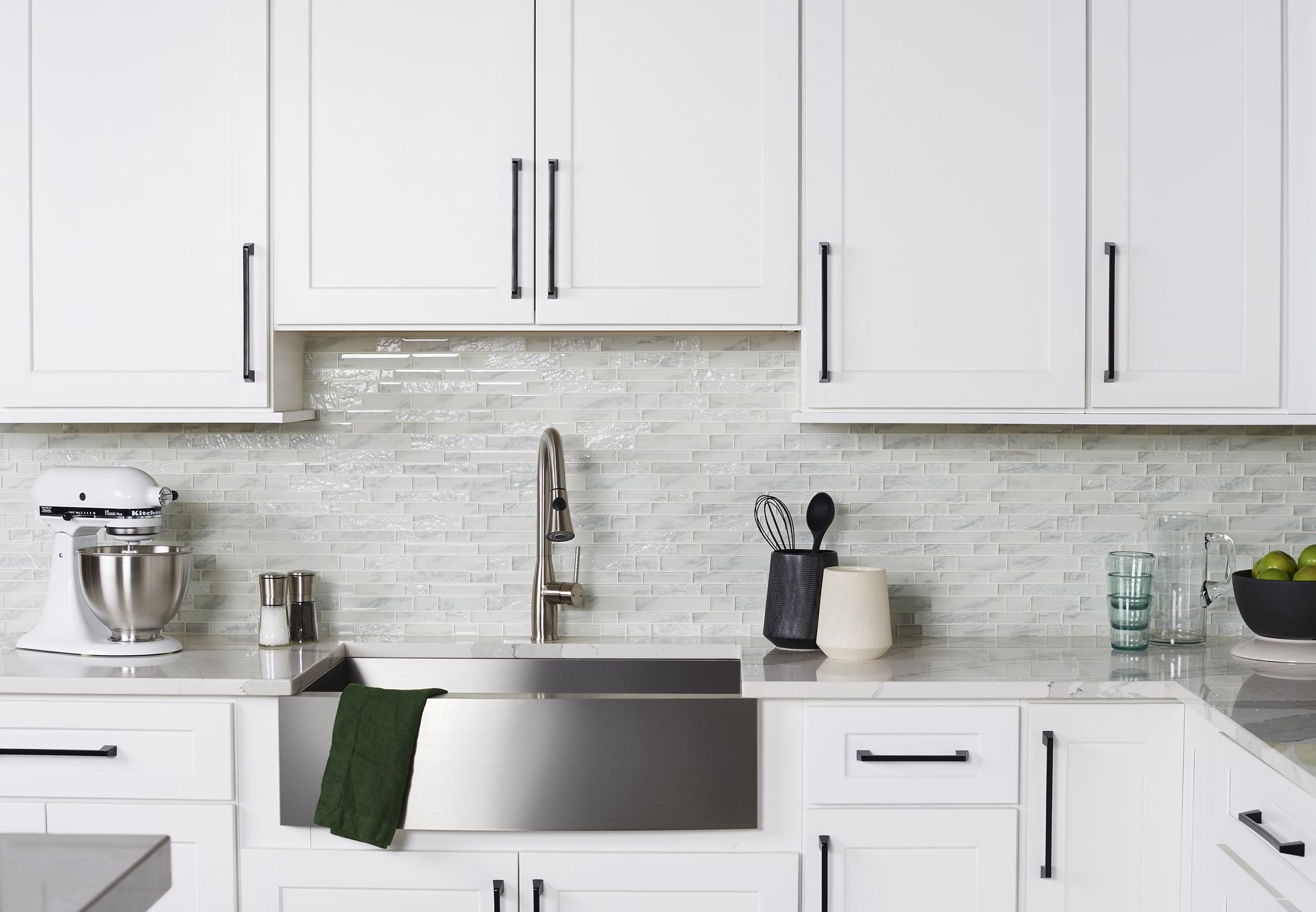 White kitchen with stainless steel sink, cabinets, and backsplash.