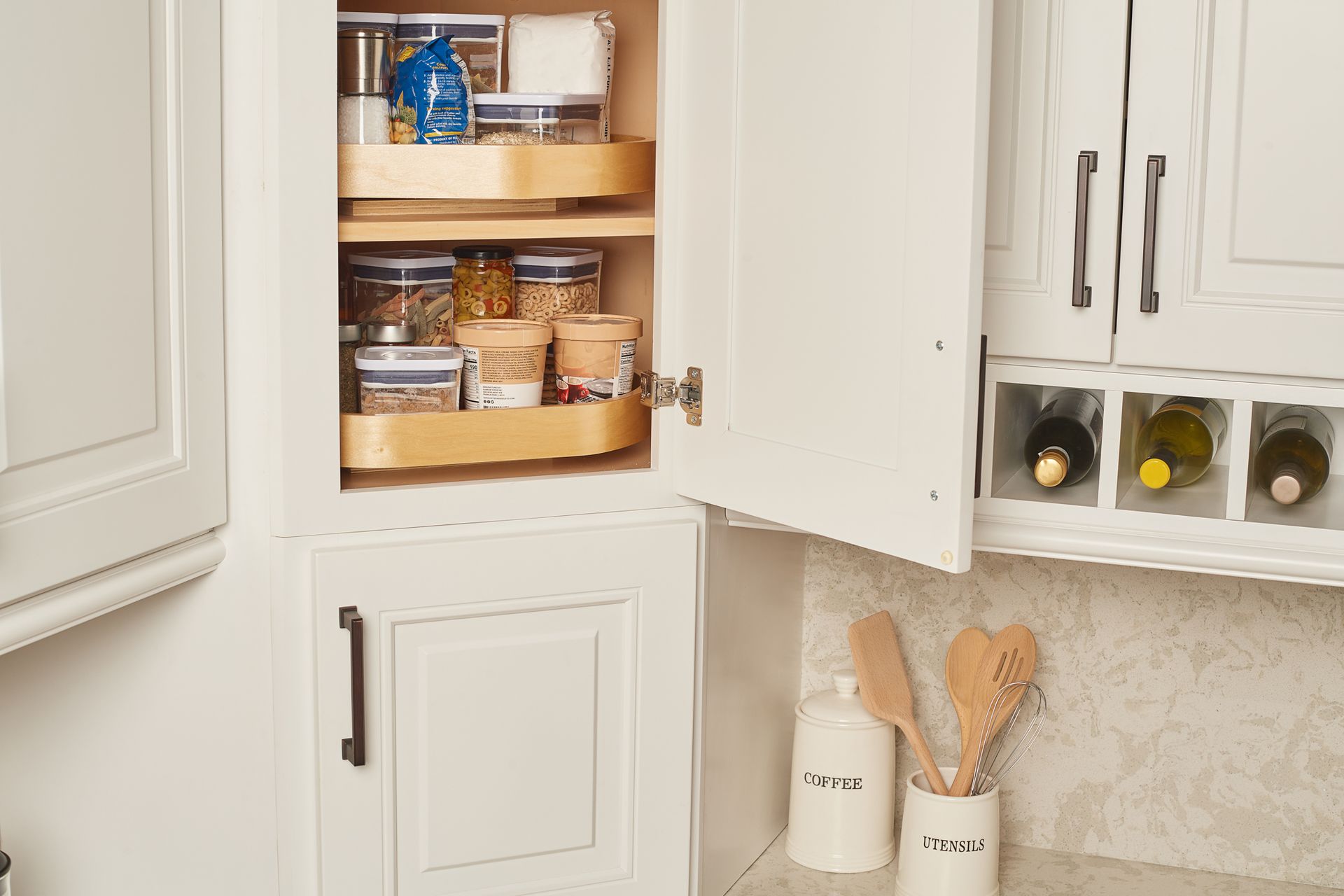 White kitchen cabinet with a pull-out lazy susan and wine rack.