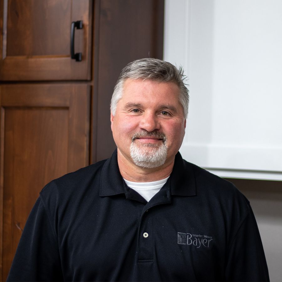 Man with graying hair and beard in a black polo shirt, smiling at the camera.