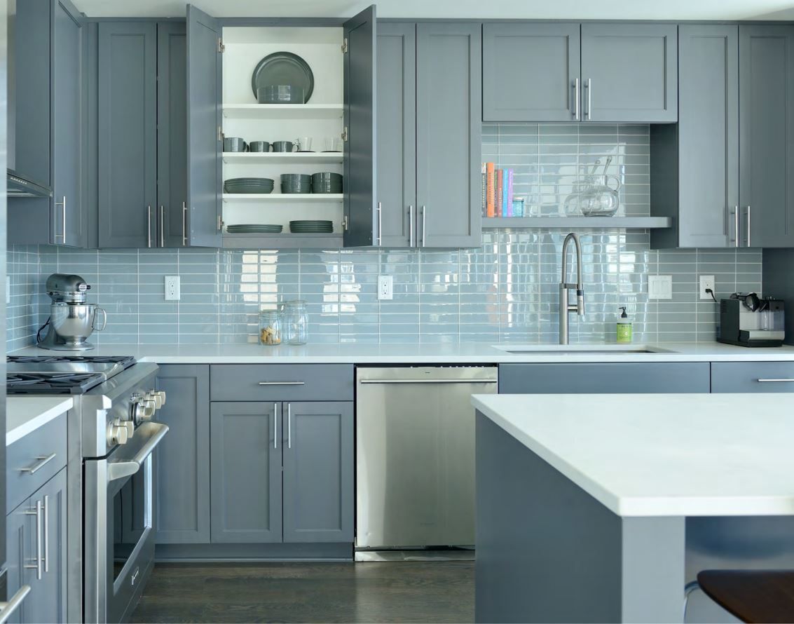 Gray kitchen with tile backsplash, cabinets, and island. Stainless steel appliances and white countertops.