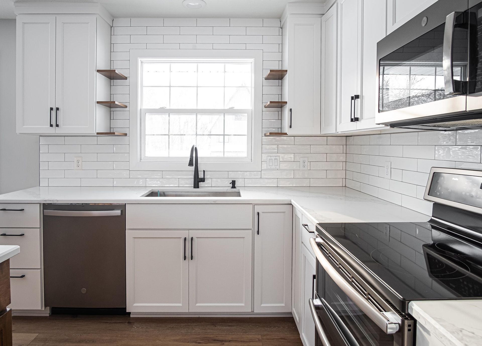 White kitchen with white cabinets, appliances, and subway tile backsplash.