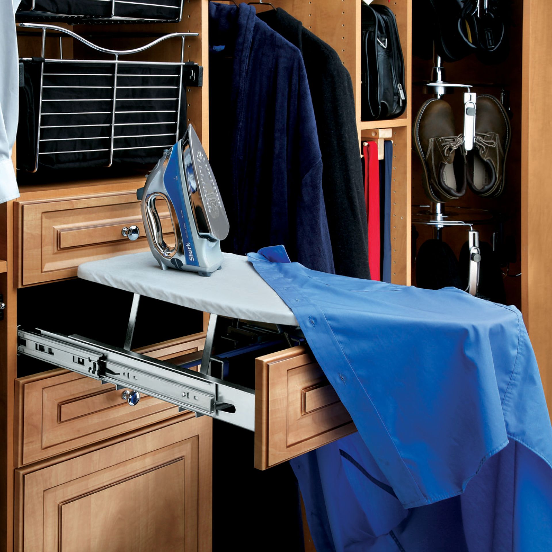 Built-in closet with pull-out ironing board and iron; blue shirt draped over board, suits hanging.
