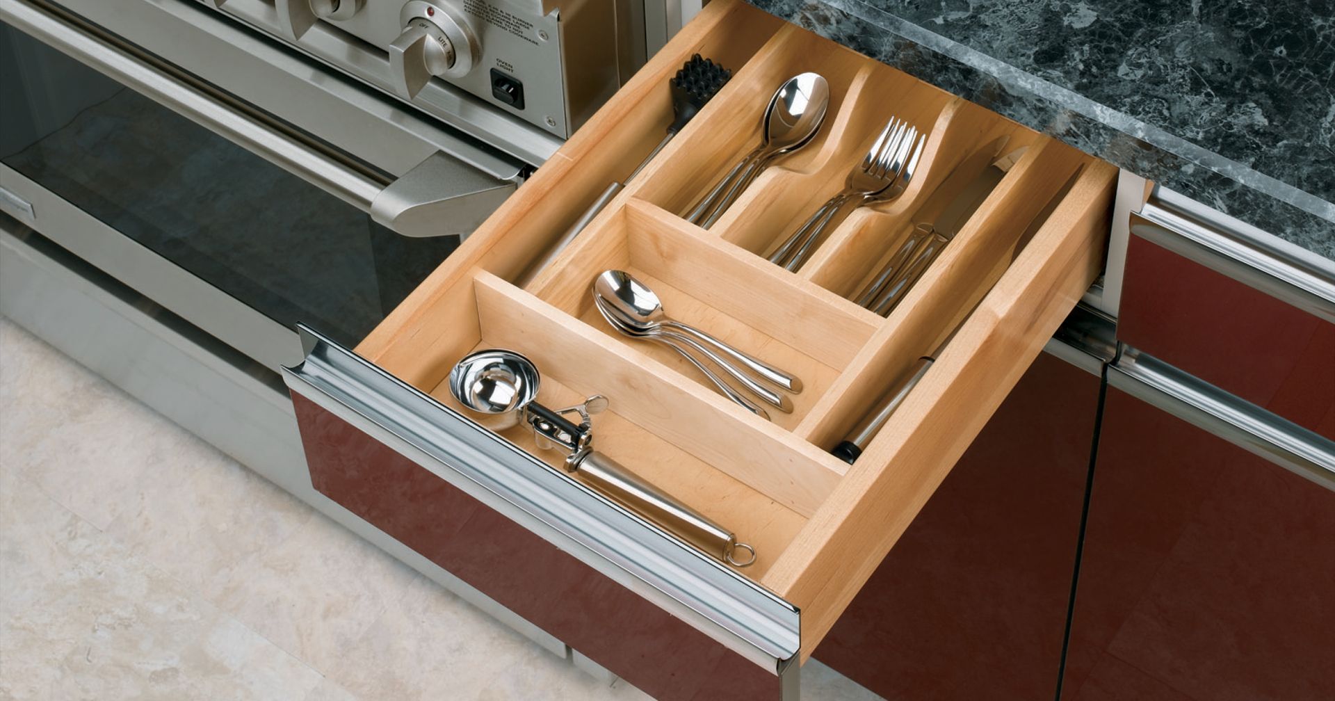 Wooden kitchen drawer open with silverware inside.