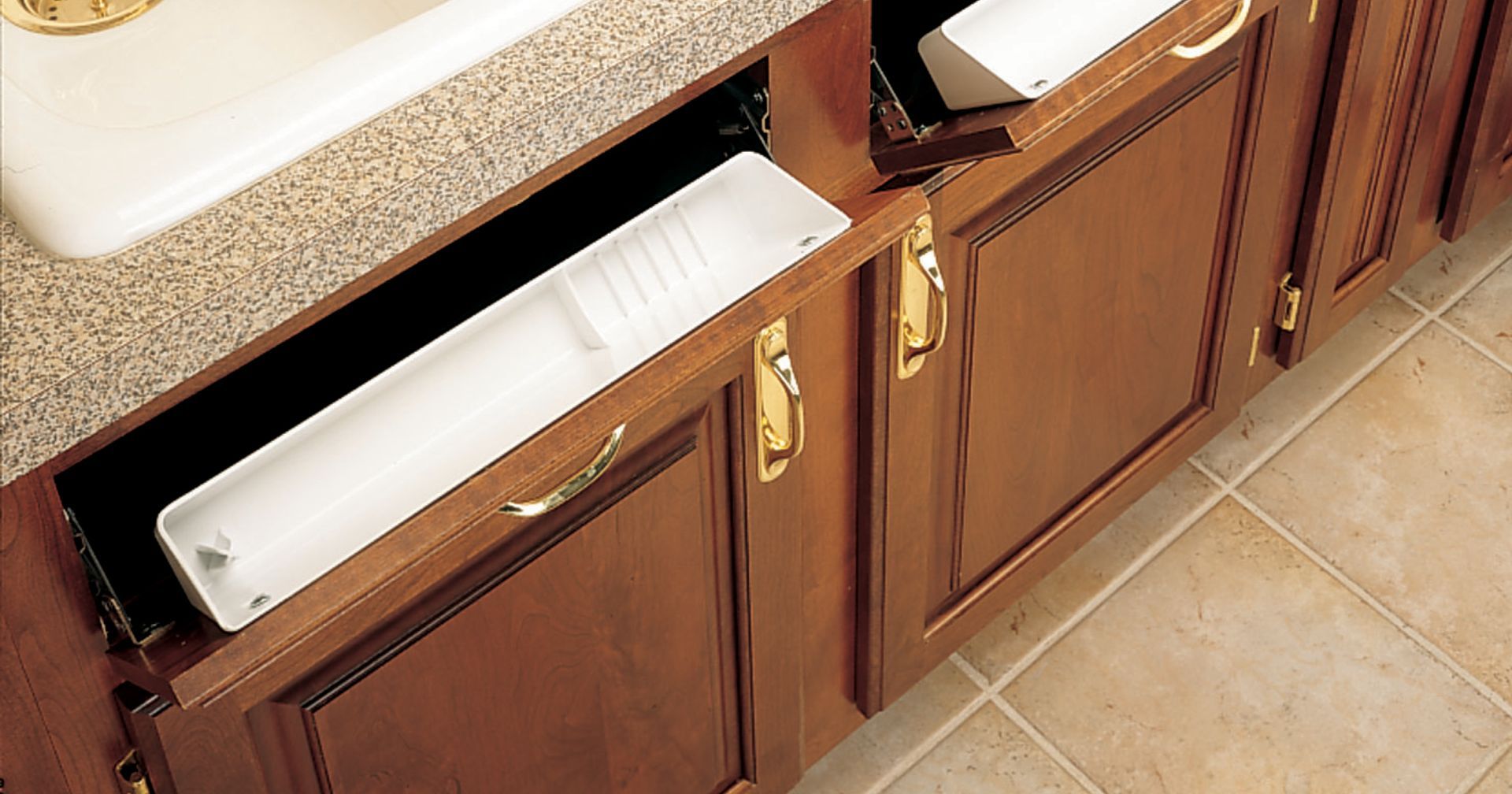 A pull-out drawer in a wooden cabinet, holding a long, white item. Beige countertop and tile floor visible.