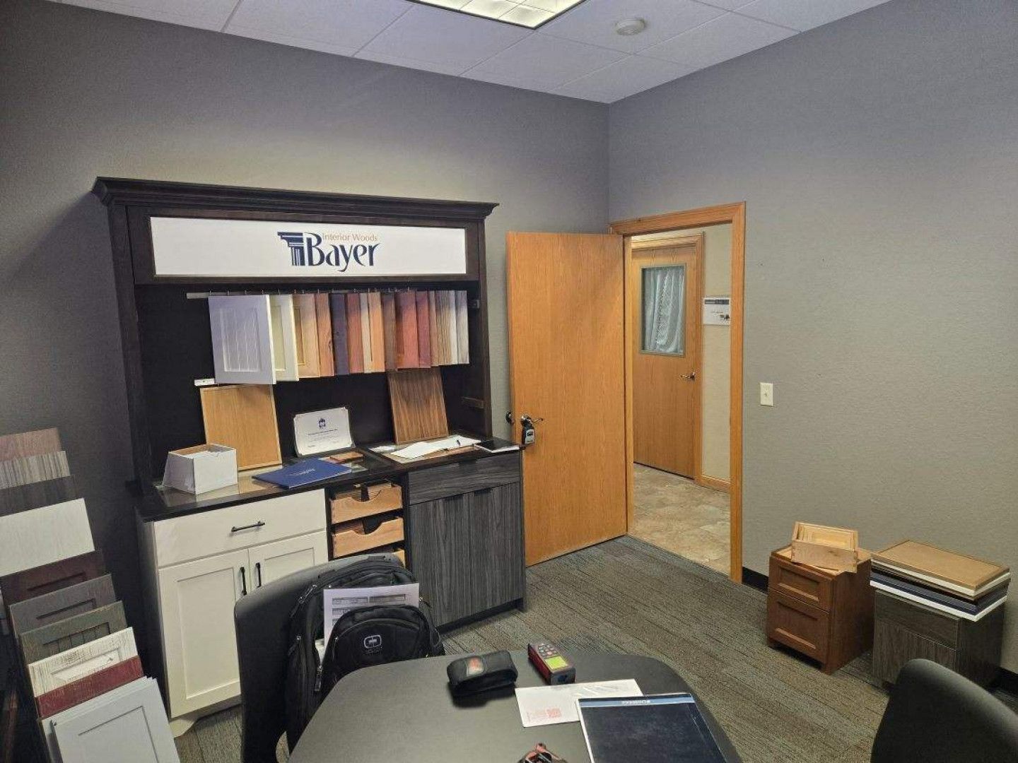 Office interior with a cabinet display, samples, an open door, and a conference table.