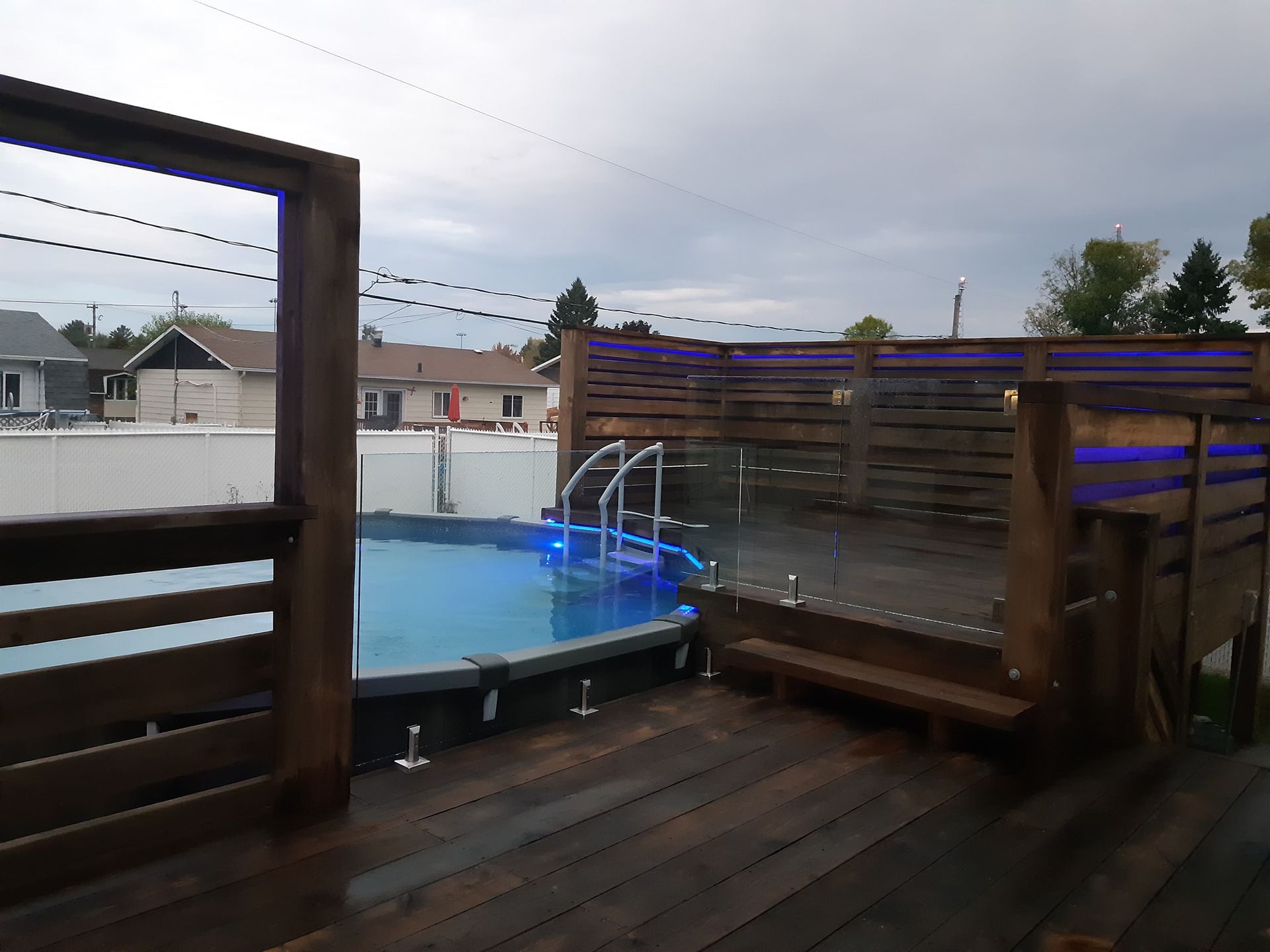 Une grande piscine est entourée d'une terrasse en bois.