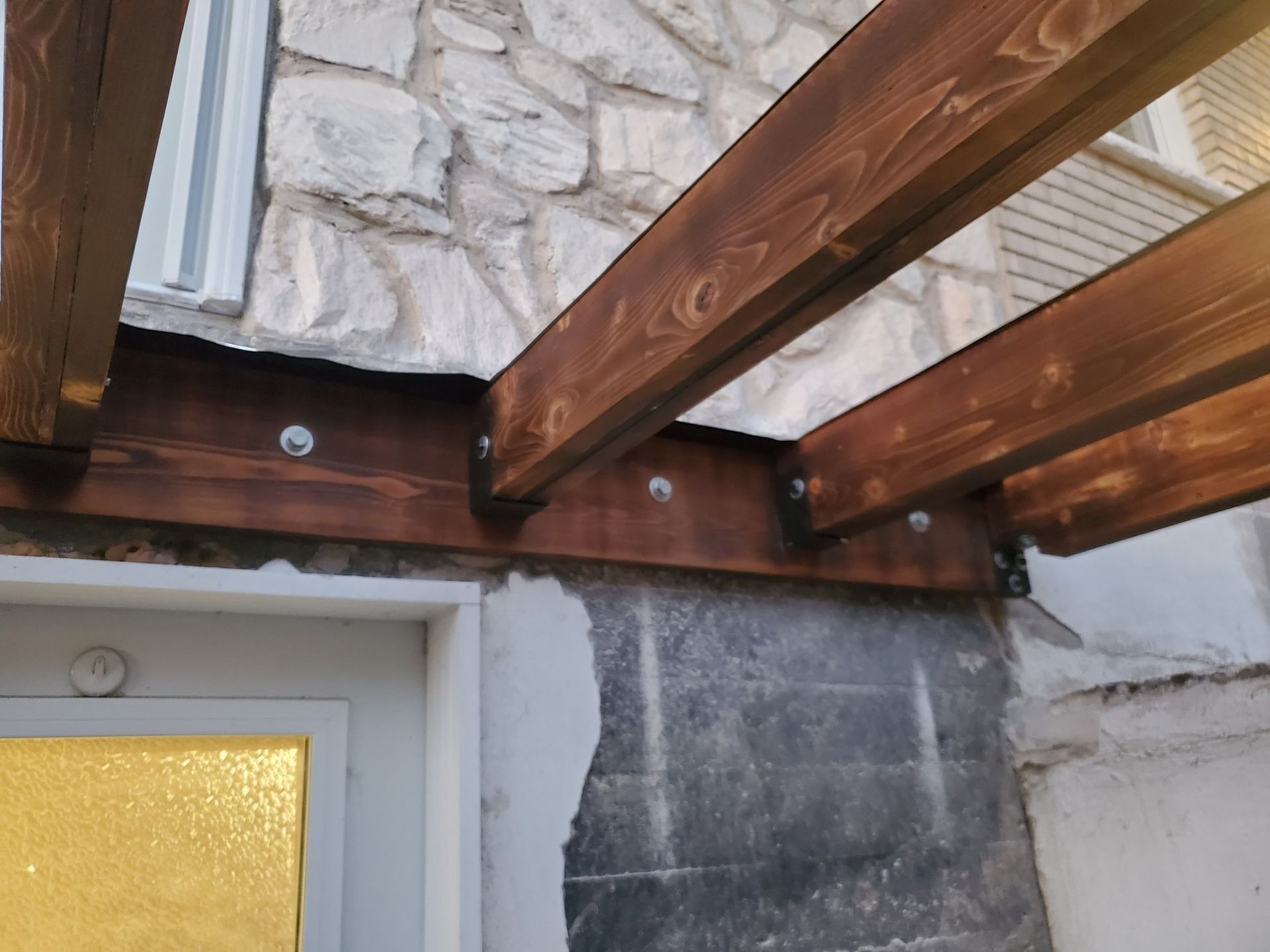 Une structure en bois est fixée à un mur en pierre