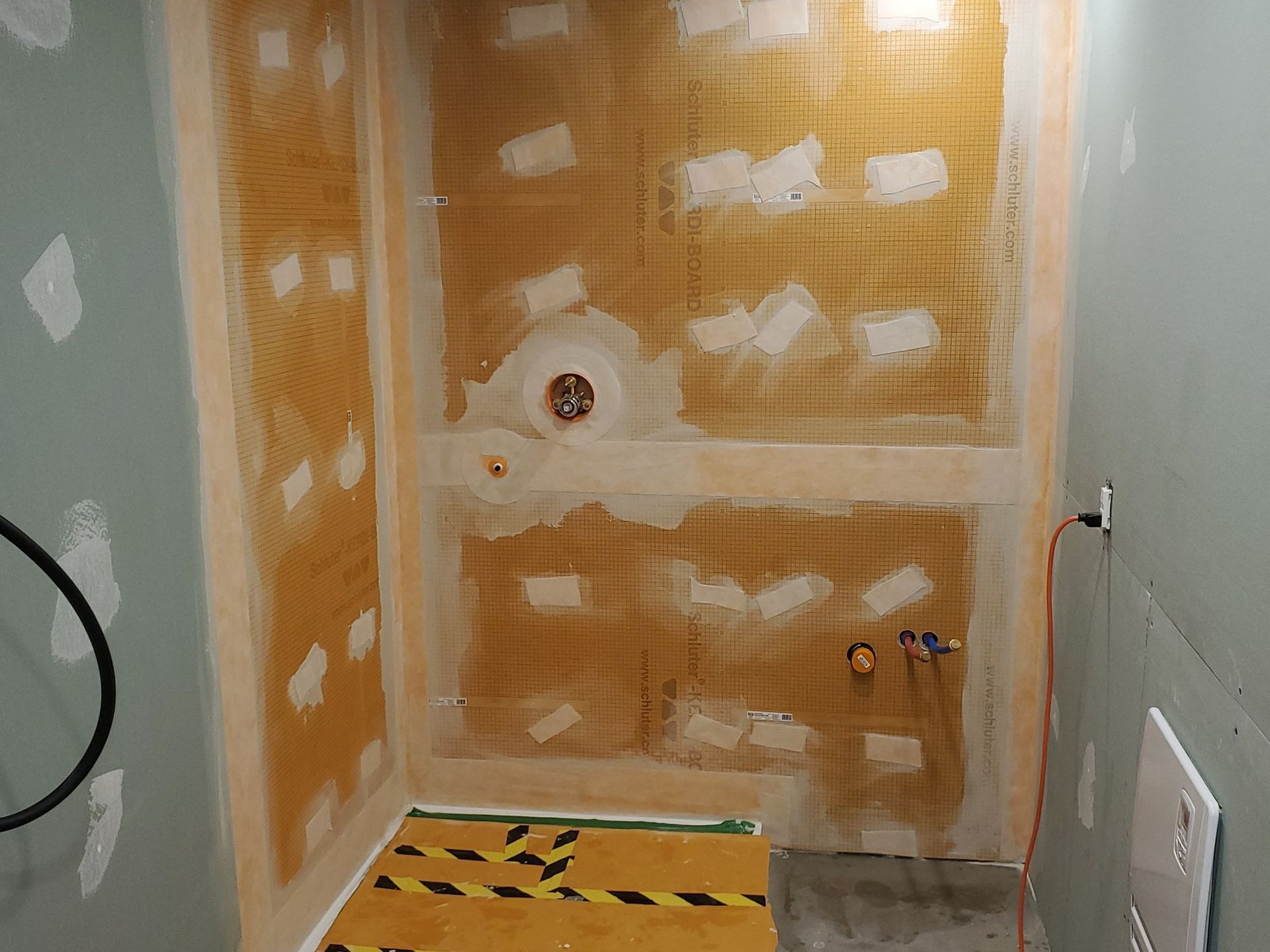 Une salle de bain en construction avec un ruban jaune et noir sur le sol.