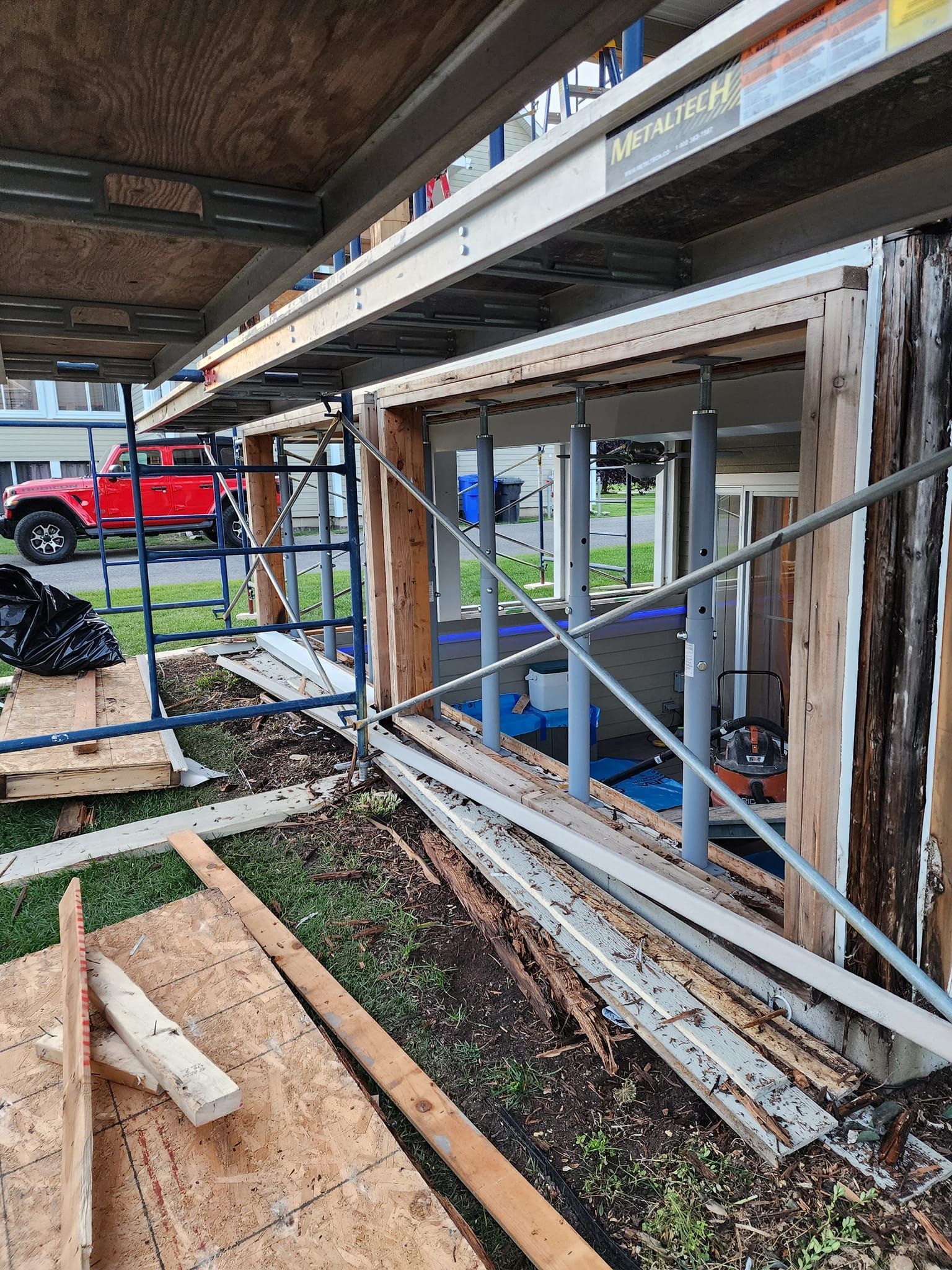 Un camion rouge est garé devant un bâtiment en construction.