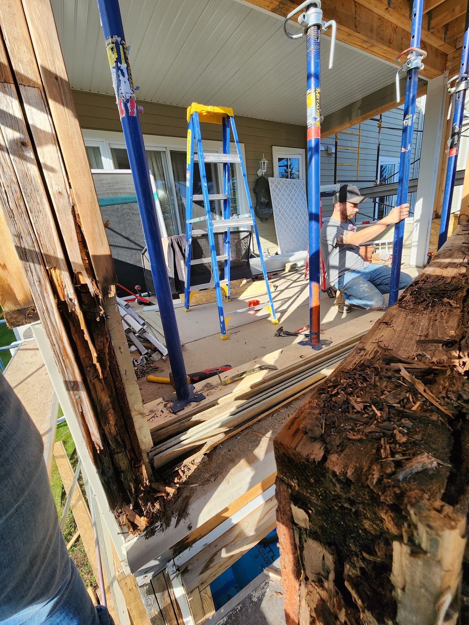 Une échelle est posée sur un tas de bois dans une pièce.